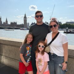 Mara Lucas with her family standing in front of the River Thames, Big Ben and Parliament House in the background