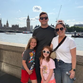 Mara Lucas with her family standing in front of the River Thames, Big Ben and Parliament House in the background
