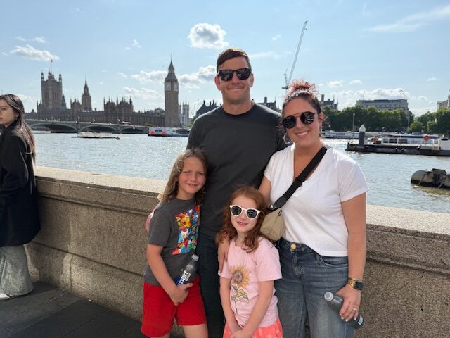Mara Lucas with her family standing in front of the River Thames, Big Ben and Parliament House in the background